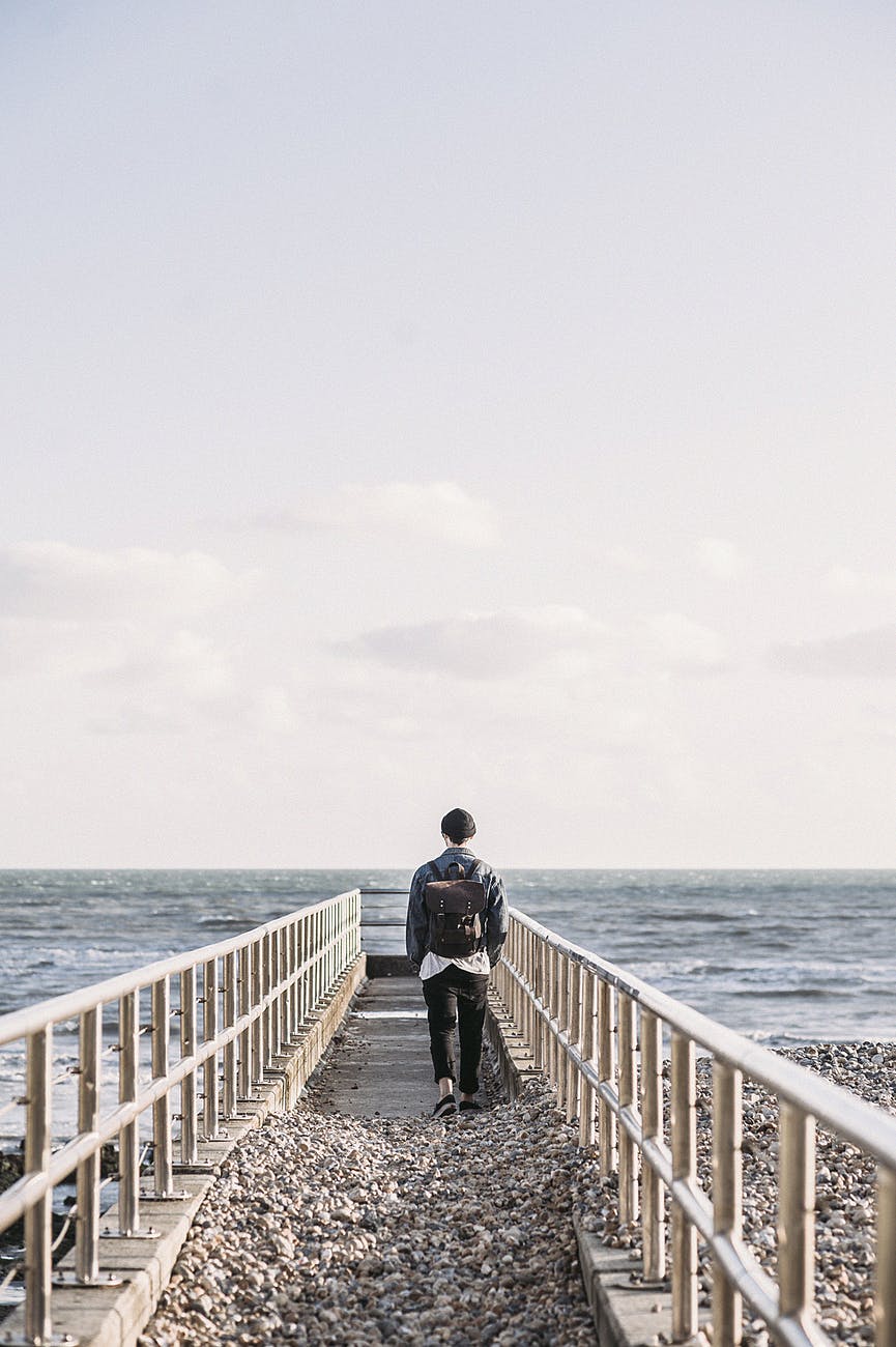 man in black jacket walking on gray concrete dock