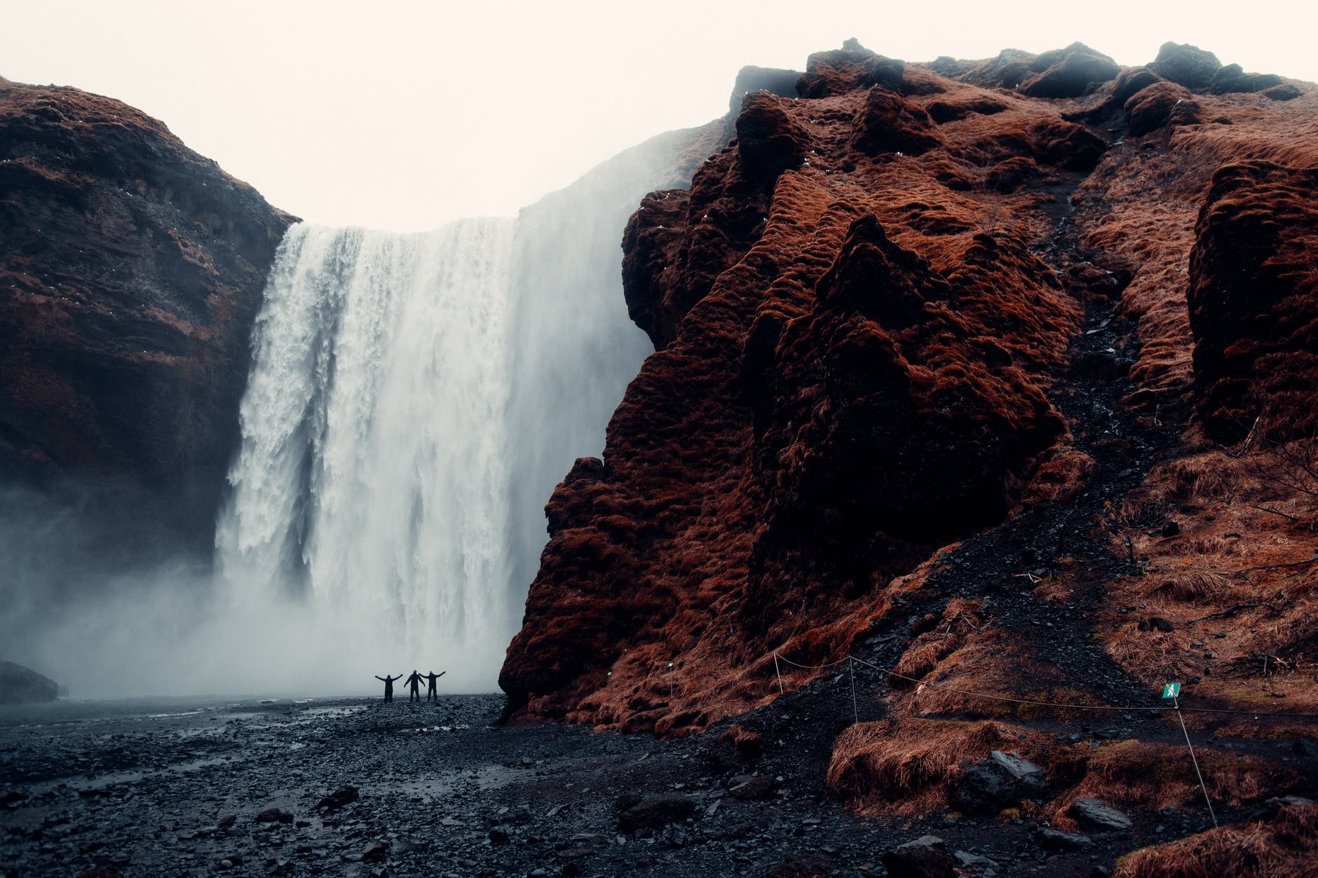 three men standing near waterfalls