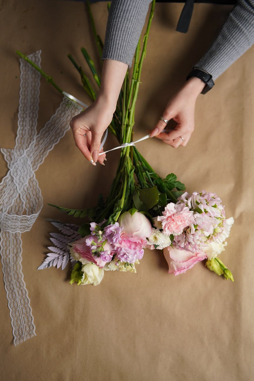 florist tying bouquet of lush flowers in workshop