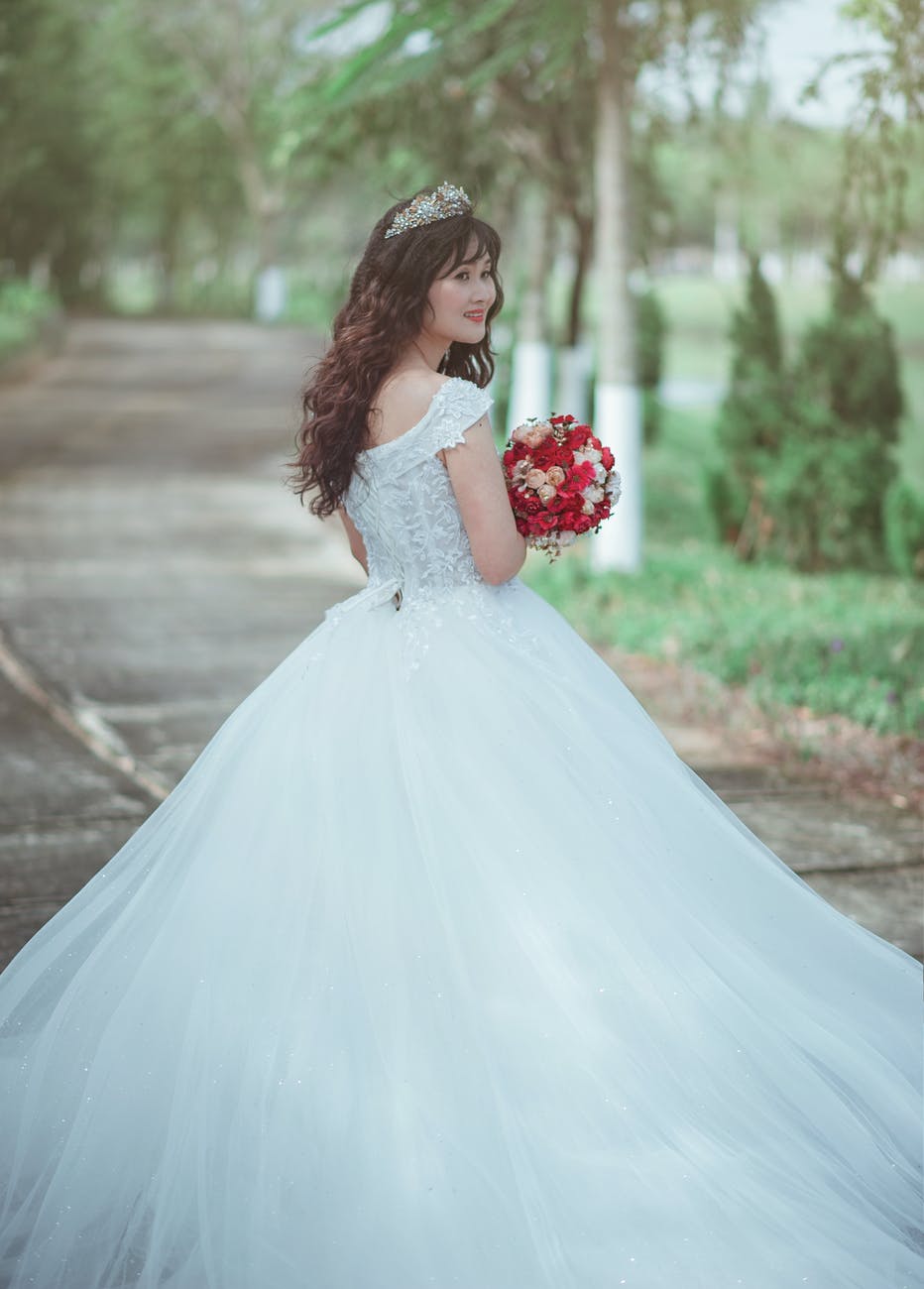 woman in white wedding dress holding red bouquet